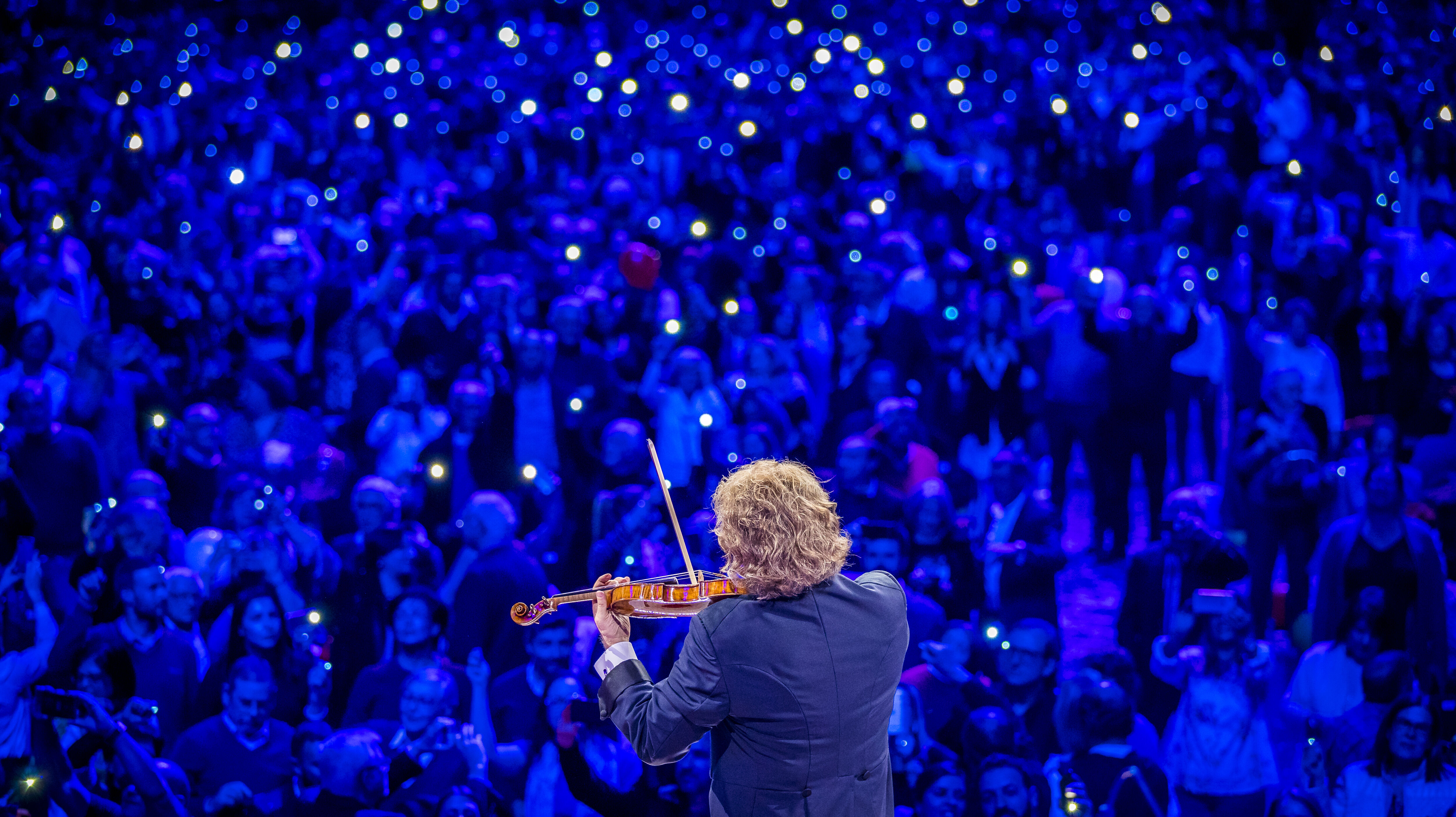 André Rieu spielt vor seinen Fans mit Leuchtmitteln in der Hand Violine.